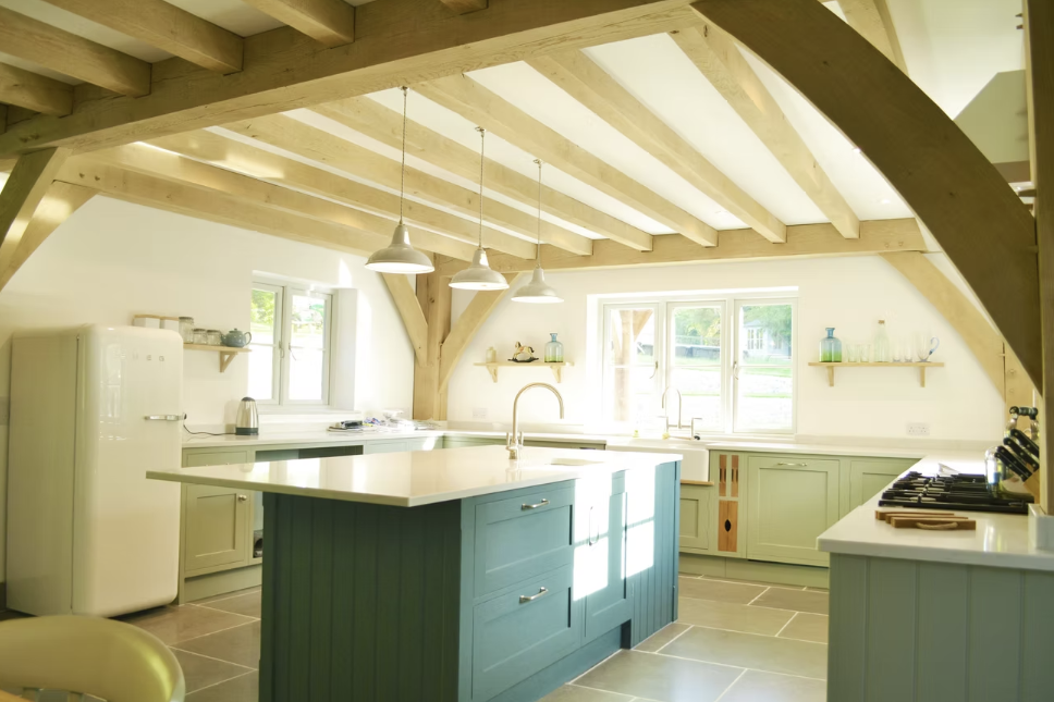 Shaker kitchen with green island and oak beams